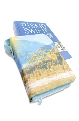 Wodoodporna okładka na Biblię Tysiąclecia oazową 12x18 we wzorze D12 z motywem gór i cytatem z Księgi Izajasza, zapinana na zamek, obok Biblia Pallottinum
